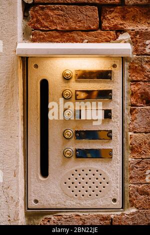 Close-ups of building facades in Venice, Italy. An old vintage intercom and a mailbox on a stone wall. On door where placed this old rusty doorbells. Stock Photo