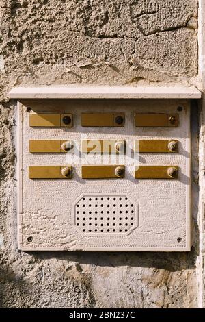 Close-ups of building facades in Venice, Italy. An old vintage intercom and a mailbox on a stone wall. On door where placed this old rusty doorbells. Stock Photo