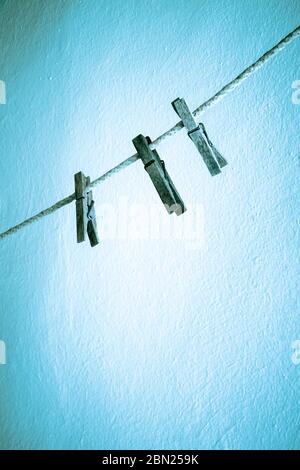 Three old wooden clothes pegs on a washing line Stock Photo