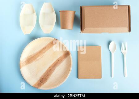 Eco friendly disposable tableware flat lay on light blue background.  Stock Photo