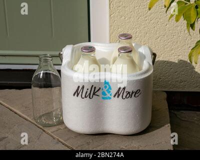 Demand for Milk and More home delivery service grows during Coronavirus lockdown. Image shows milk bottles with Milk & More delivery box on doorstep Stock Photo