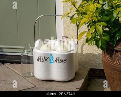Demand for Milk and More home delivery service grows during coronavirus lockdown. Image shows milk bottles with Milk & More delivery box on doorstep Stock Photo
