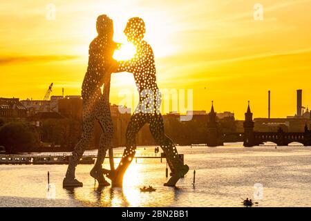 Berlin, Deutschland. 08th May, 2020. 08.05.2020, the aluminum sculpture Molecule Man by Jonathan Borofsky in Berlin's Osthafen or Mediaspree/Mediahafen in Alt-Treptow at sunset in versus light. The 30 meter high three-person sculpture was erected in the Spree between Elsenbrucke and Oberbaumbrucke near the intersection of the three districts of Kreuzberg, Alt-Treptow and Friedrichshain and is a must-see. In the background you can see the Oberbaum Bridge. | usage worldwide Credit: dpa/Alamy Live News Stock Photo