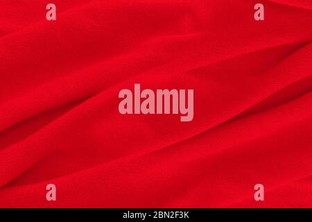 Red fabric texture background. Abstract cloth backdrop with soft waves. Stock Photo