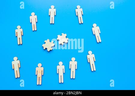 Business concept, trying to find a solution to a problem by arranging and matching puzzle pieces on blue background, top view. Wooden people Stock Photo
