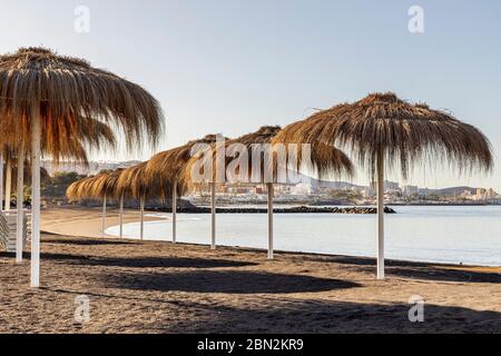 Sunshade umbrellas on empty beach at Playa Beril, Costa Adeje, Tenerife, Canary Islands, Spain Stock Photo