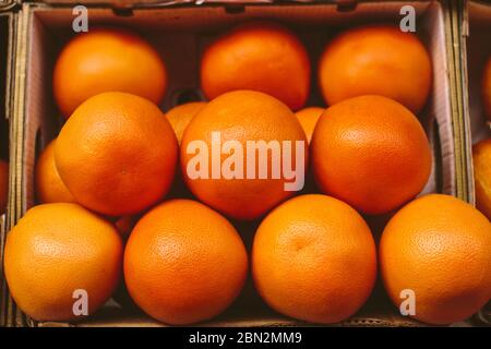 Fresh ripe grapefruits in a carton box on a fruit market, organic natural food background Stock Photo