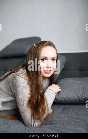 Close-up portrait of young self assured female in gray home interior, modern trendy attractive woman looking at camera Stock Photo