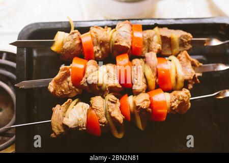 Pieces of raw chopped meat with tomatoes and onion rings ready for barbecue. Chicken barbecue, top view. Stock Photo