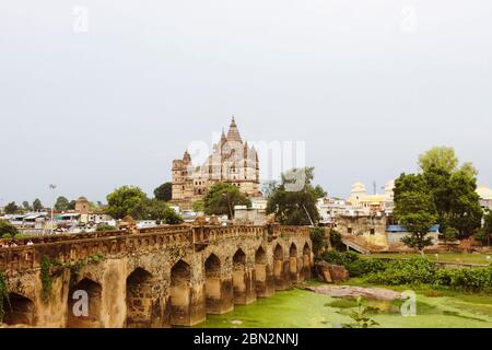 Orchha, Madhya Pradesh, India : Mughal bridge over the Betwa river with Chaturbhuj Temple in background. Stock Photo