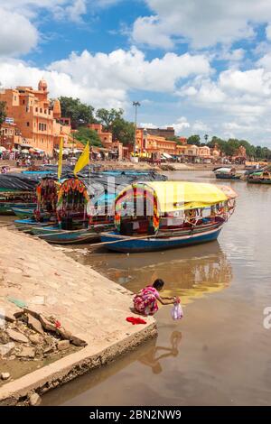 Chitrakoot, Madhya Pradesh, India : A woman does laundry by the colourful boats lining near the steps of Ramghat on the Mandakini river. Stock Photo