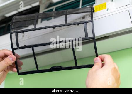Male technician repairing and reading air conditioners. Cover opening and close-up of one filter Stock Photo