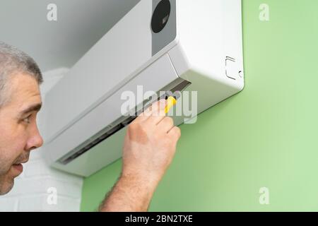 Male technician repairing and diagnosing air conditioners. Diagnostics for errors and preparation of a repair plan Stock Photo