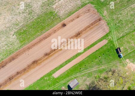 Tractor with trailer fertilizer manure transports to the field before sowing crops, potatoes. Aerial height view Stock Photo