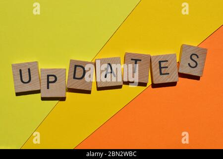 Updates, word in 3d wooden alphabet letters on orange and yellow background Stock Photo