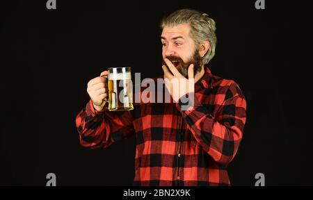 surprised male brewer. brutal hipster drink beer. mature bearded man hold beer glass. mug of alcohol beverage. confident bartender. barman in bar. resting at pub. Cheers. sport bar. trying a new beer. Stock Photo