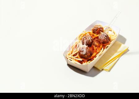 Italian spaghetti and meatballs with tomato sauce in takeaway packaging box on white background with shadow.Restaurant food delivery concept Stock Photo