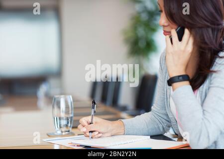 Businesswoman talking on smart phone and doing paperwork Stock Photo