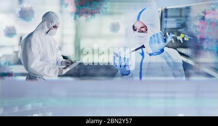 Scientists in clean suits studying coronavirus in laboratory Stock Photo