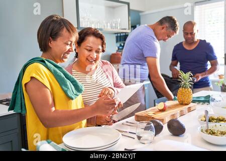 Happy couple friends using digital tablet and cooking in kitchen Stock Photo
