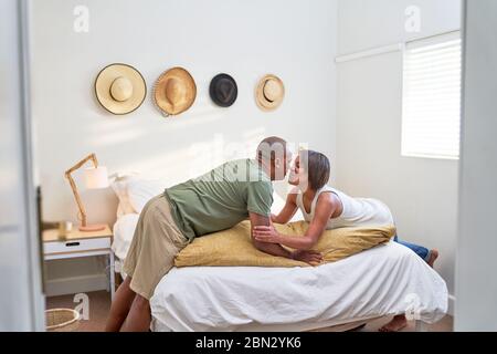 Affectionate couple kissing over bed in bedroom Stock Photo