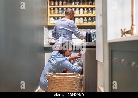 Couple doing dishes and laundry in kitchen Stock Photo