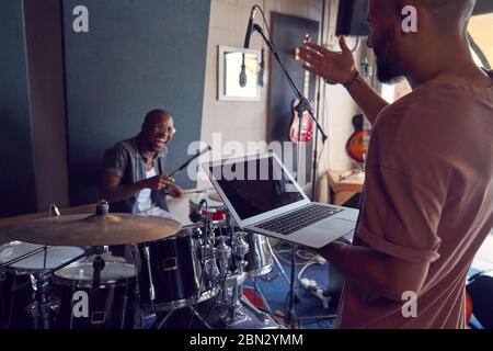 Happy musicians with drums and laptop in recording studio Stock Photo