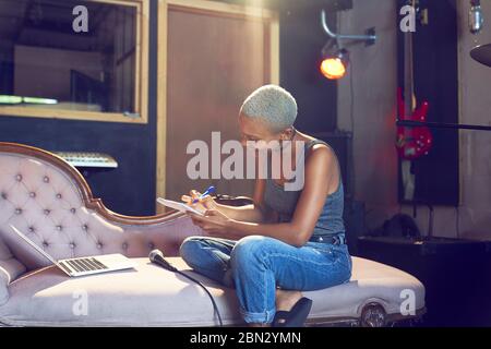 Female musician song writing on chaise lounge Stock Photo