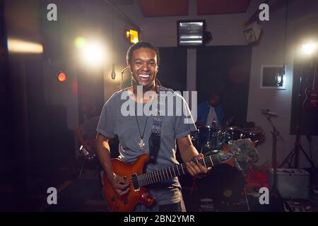 Portrait confident male musician playing guitar in recording studio Stock Photo