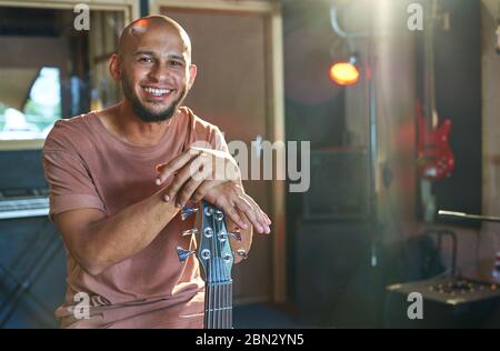 Portrait happy confident male musician with guitar in recording studio Stock Photo