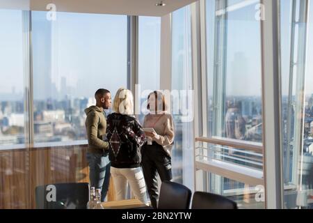 Business people talking at sunny highrise office window
