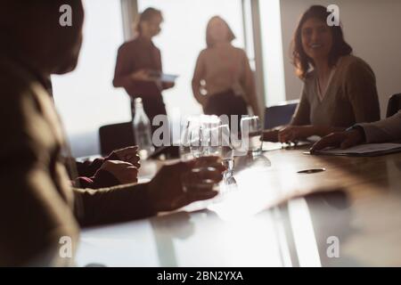 Business people talking in sunny conference room meeting