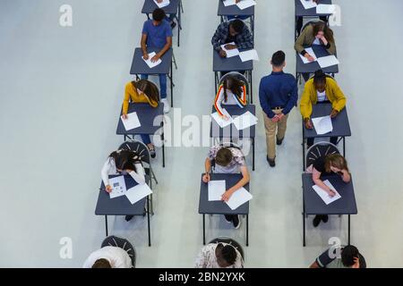 High school teacher supervising students taking exam at desks Stock Photo