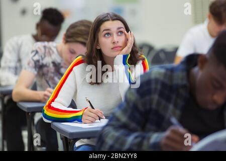 Focused high school girl student taking exam looking up Stock Photo