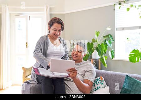 Mature couple using digital tablet on living room sofa Stock Photo