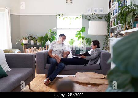 Happy mature couple using digital tablet on living room sofa Stock Photo