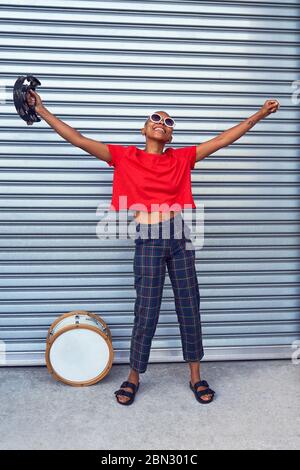 Portrait carefree young female musician with tambourine Stock Photo