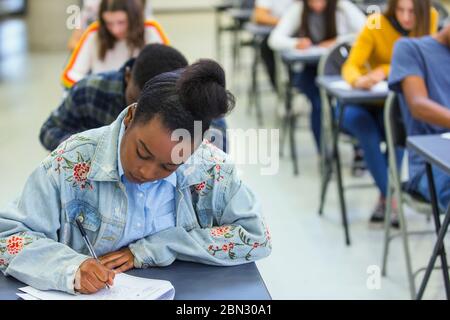 Focused high school girl student taking exam at desk in classroom Stock Photo