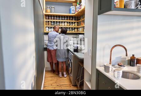 Couple talking and doing dishes in kitchen Stock Photo