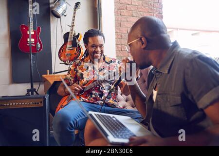 Happy male musicians practicing in recording studio Stock Photo