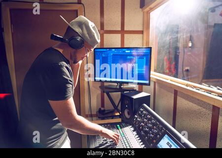 Male music producer working at sound board in recording studio Stock Photo