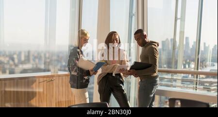 Business people discussing paperwork in sunny urban office Stock Photo