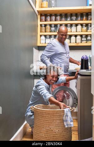 Happy couple doing laundry in kitchen Stock Photo
