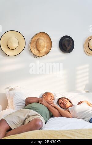 Happy affectionate couple relaxing and talking on bed Stock Photo