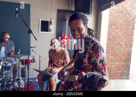 Smiling male musicians practicing in garage recording studio Stock Photo