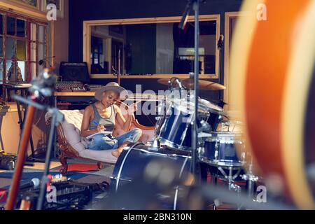 Female musician song writing in recording studio Stock Photo