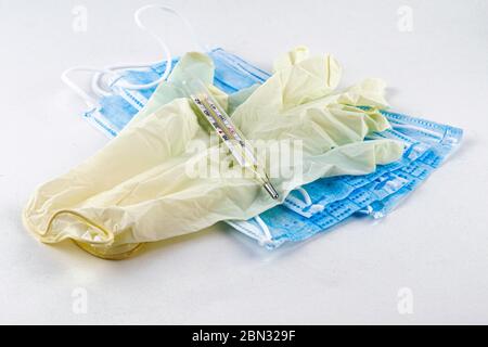 medical hygiene protective masks, rubber gloves and thermometer on a white background Stock Photo