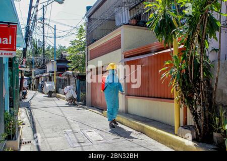 Mandaluyong City, Philippines. 12th May, 2020. A health worker sprays disinfectant at a village under lockdown in Mandaluyong City, the Philippines, on May 12, 2020. Philippine government announced on Tuesday that Metro Manila, Laguna province in the main island of Luzon, and Cebu City in the central Philippines will be placed under 'modified enhanced community quarantine' from May 16 to May 31, or after the lockdown period in many parts of the country lapses in May 15. Credit: Rouelle Umali/Xinhua/Alamy Live News Stock Photo