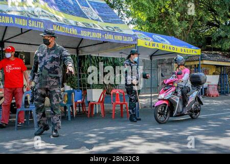 Mandaluyong City, Philippines. 12th May, 2020. Police officers work at a village under lockdown in Mandaluyong City, the Philippines, on May 12, 2020. Philippine government announced on Tuesday that Metro Manila, Laguna province in the main island of Luzon, and Cebu City in the central Philippines will be placed under 'modified enhanced community quarantine' from May 16 to May 31, or after the lockdown period in many parts of the country lapses in May 15. Credit: Rouelle Umali/Xinhua/Alamy Live News Stock Photo