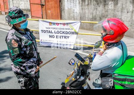 Mandaluyong City, Philippines. 12th May, 2020. A police officer inspects a motorcyclist at a village under lockdown in Mandaluyong City, the Philippines, on May 12, 2020. Philippine government announced on Tuesday that Metro Manila, Laguna province in the main island of Luzon, and Cebu City in the central Philippines will be placed under 'modified enhanced community quarantine' from May 16 to May 31, or after the lockdown period in many parts of the country lapses in May 15. Credit: Rouelle Umali/Xinhua/Alamy Live News Stock Photo